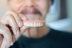 A man is holding dentures in St. Charles, MO